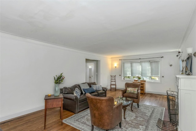 living area featuring baseboards, wood finished floors, and crown molding