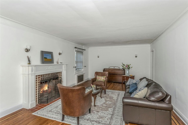 living room featuring wood finished floors, crown molding, a fireplace, and baseboards