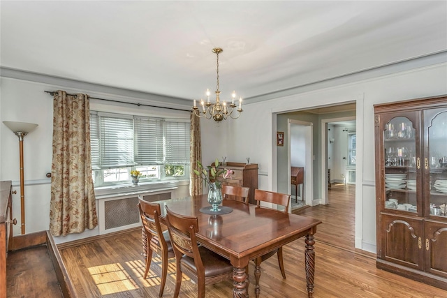 dining room with baseboards, light wood-style floors, a chandelier, and radiator heating unit