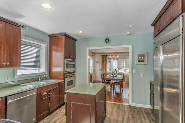 kitchen featuring light wood finished floors, an inviting chandelier, recessed lighting, a sink, and appliances with stainless steel finishes