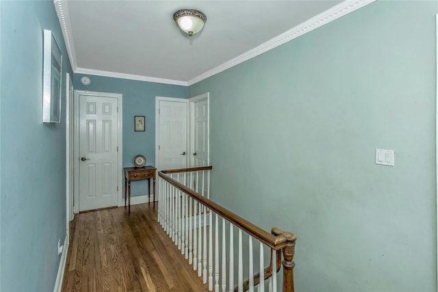 hallway with baseboards, an upstairs landing, wood finished floors, and ornamental molding