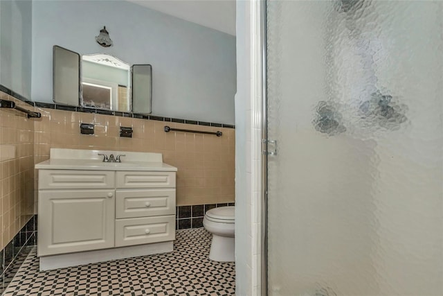 full bath with vanity, a shower stall, wainscoting, tile walls, and toilet