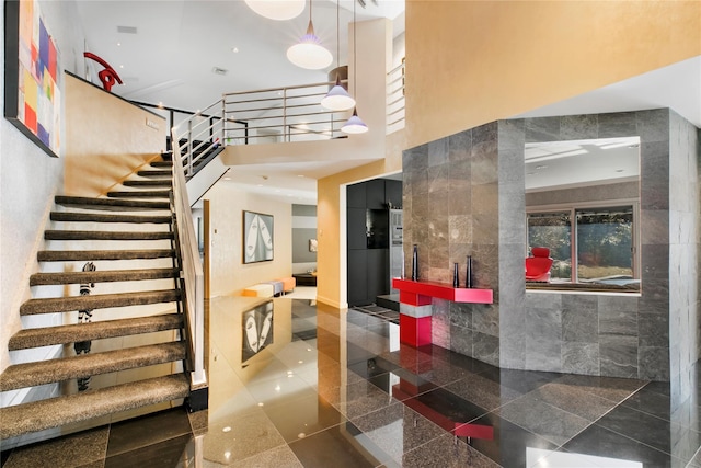 staircase with granite finish floor and a towering ceiling