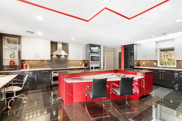 kitchen featuring stainless steel appliances, granite finish floor, wall chimney exhaust hood, and modern cabinets