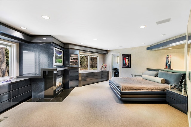 bedroom with a fireplace with flush hearth, multiple windows, visible vents, and recessed lighting