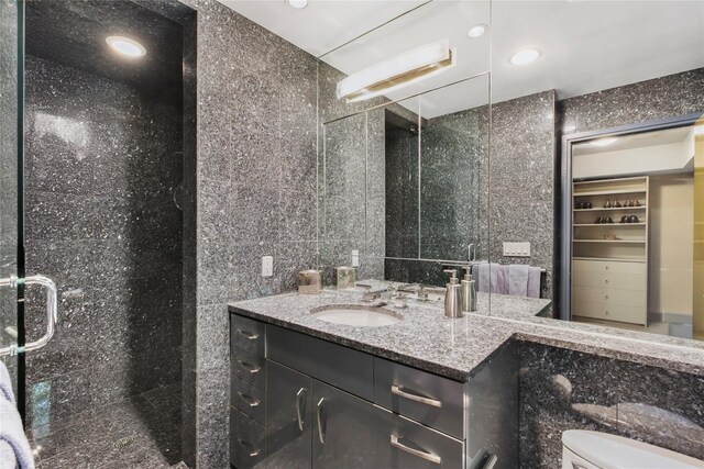 bathroom with toilet, recessed lighting, vanity, tile walls, and a shower stall