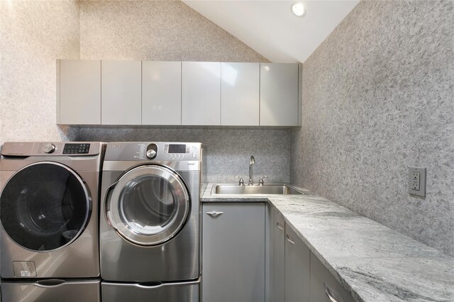 washroom featuring washing machine and dryer, a sink, and cabinet space