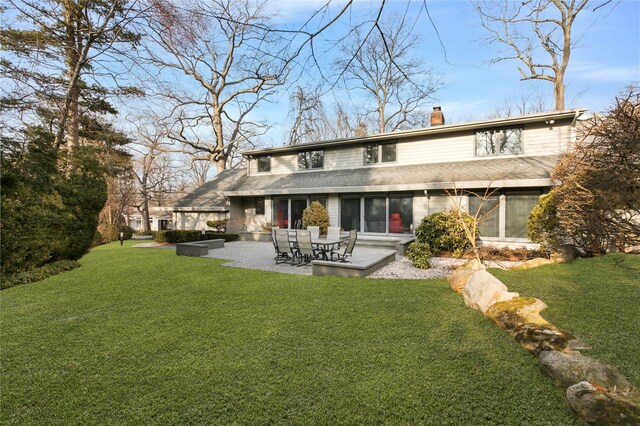 rear view of house featuring a patio area, a chimney, and a lawn