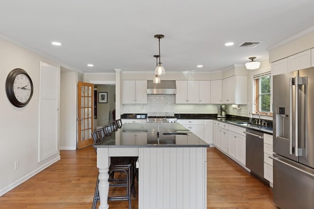 kitchen featuring a sink, wall chimney range hood, light wood-style floors, and stainless steel appliances