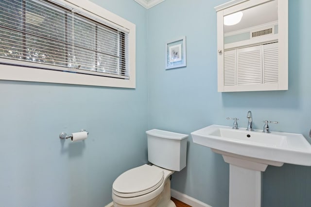 half bathroom with toilet, baseboards, and a sink