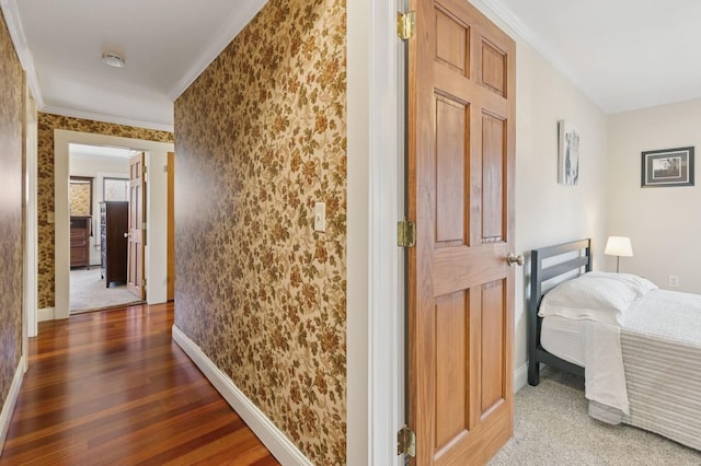 hallway featuring wallpapered walls, wood finished floors, baseboards, and ornamental molding