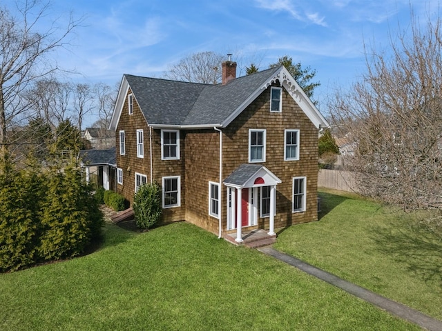 rear view of house featuring a lawn, a chimney, roof with shingles, and fence