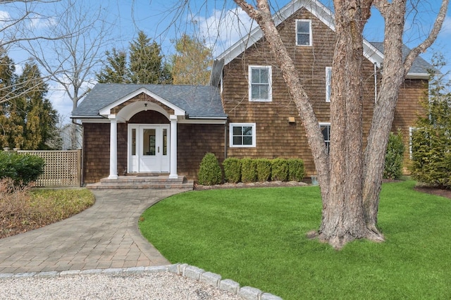 shingle-style home with a shingled roof and a front lawn