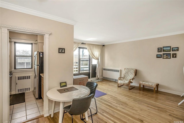 dining space with crown molding, light wood-type flooring, baseboards, and radiator