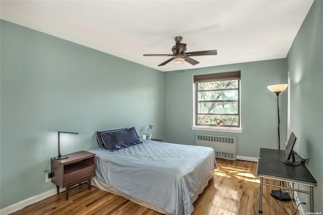 bedroom featuring ceiling fan, radiator heating unit, hardwood / wood-style flooring, and baseboards