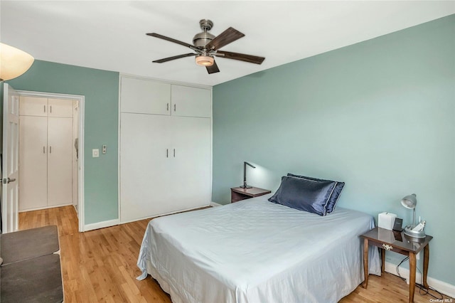 bedroom featuring baseboards, ceiling fan, a closet, and light wood-style floors