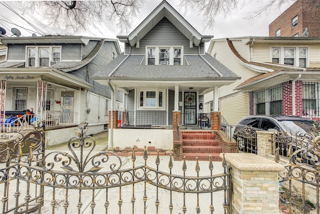 view of front of property featuring a porch, a gate, a shingled roof, and a fenced front yard