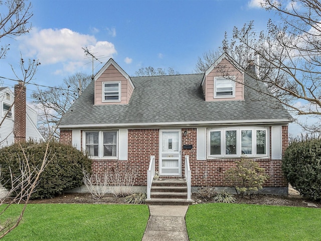 cape cod home with brick siding, a front lawn, and a shingled roof