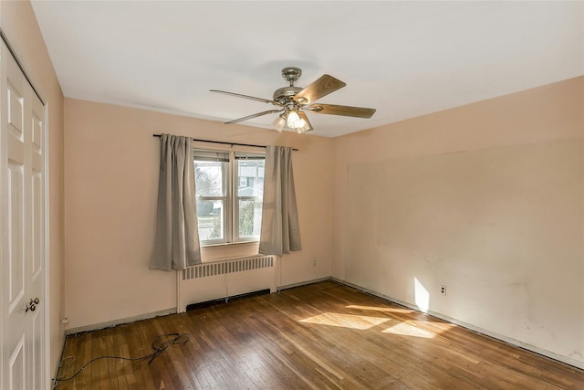 spare room with hardwood / wood-style floors, radiator heating unit, baseboards, and ceiling fan