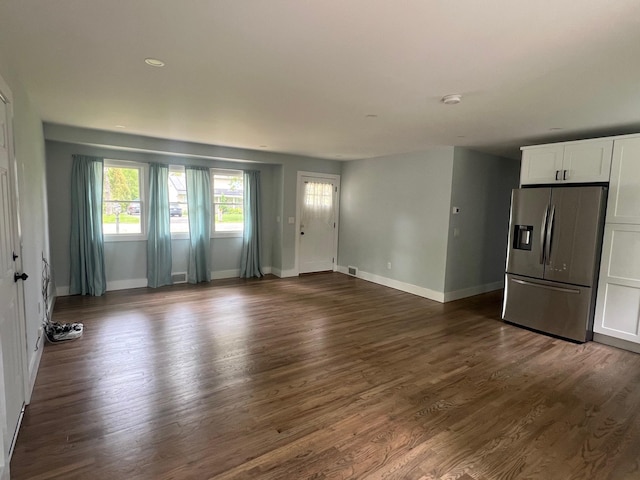 unfurnished living room with baseboards and dark wood-type flooring