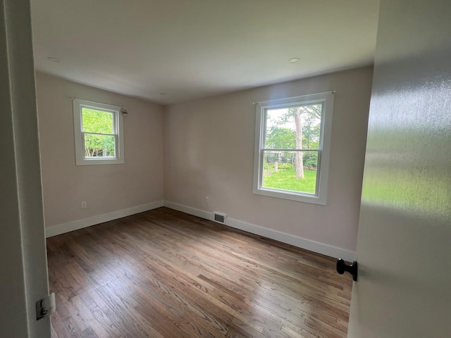 unfurnished room featuring wood finished floors, visible vents, and baseboards