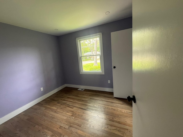 spare room with visible vents, baseboards, and wood finished floors