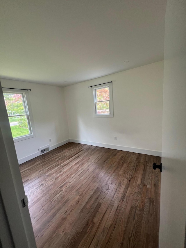 unfurnished room featuring visible vents, baseboards, and dark wood-style flooring