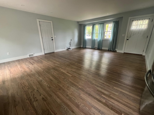 unfurnished living room featuring visible vents, baseboards, and dark wood-style floors