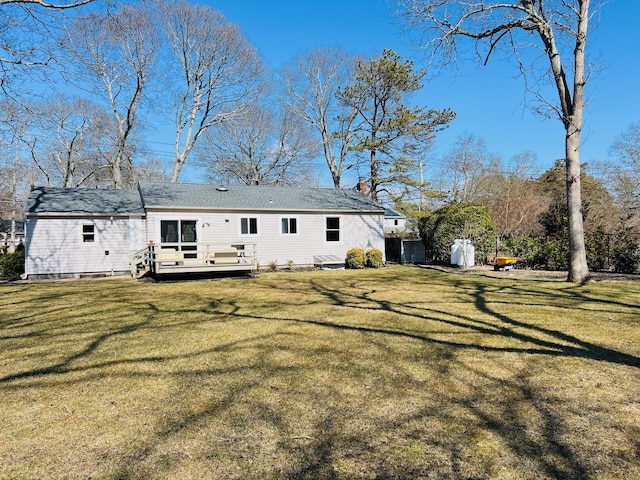 rear view of property featuring a lawn and a deck