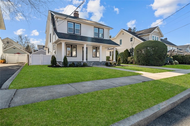 view of front of property with a chimney, a porch, roof with shingles, fence, and a front lawn