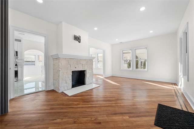 unfurnished living room featuring a stone fireplace, wood finished floors, and recessed lighting