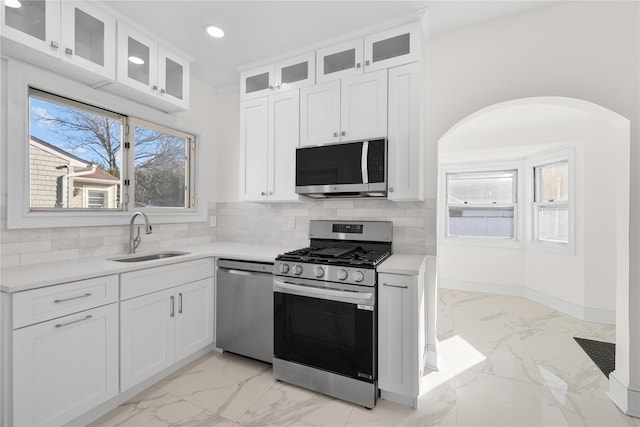 kitchen with decorative backsplash, marble finish floor, stainless steel appliances, a sink, and recessed lighting