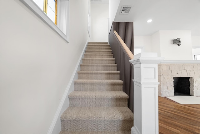 stairs with recessed lighting, a fireplace, wood finished floors, visible vents, and baseboards