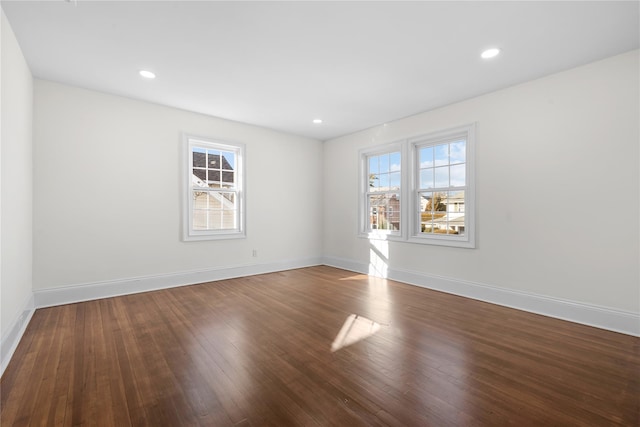 empty room with plenty of natural light, baseboards, and wood finished floors