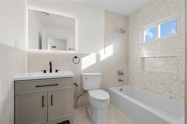 full bathroom with tile walls, visible vents, toilet, vanity, and  shower combination