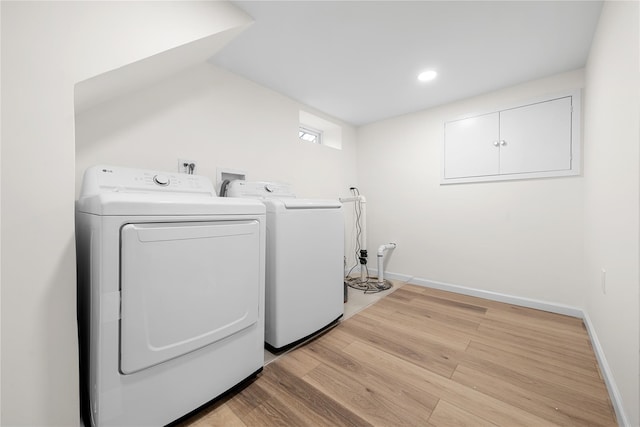 washroom featuring laundry area, washer and clothes dryer, light wood-type flooring, and baseboards