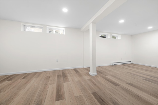 below grade area featuring a baseboard heating unit, recessed lighting, a wealth of natural light, and light wood-style floors