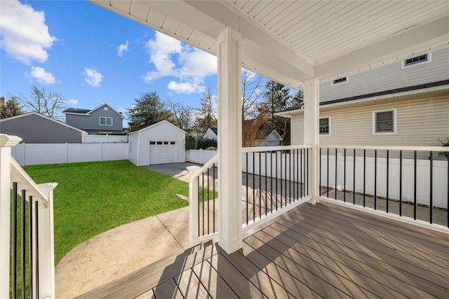 deck featuring a detached garage, a lawn, fence, driveway, and an outdoor structure