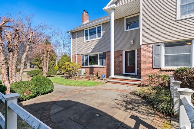 exterior space featuring brick siding and a chimney