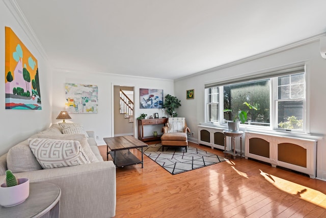 living room with stairway, radiator heating unit, wood-type flooring, and ornamental molding