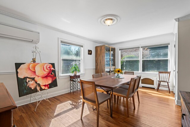 dining room featuring a wall mounted air conditioner, baseboards, crown molding, and hardwood / wood-style flooring