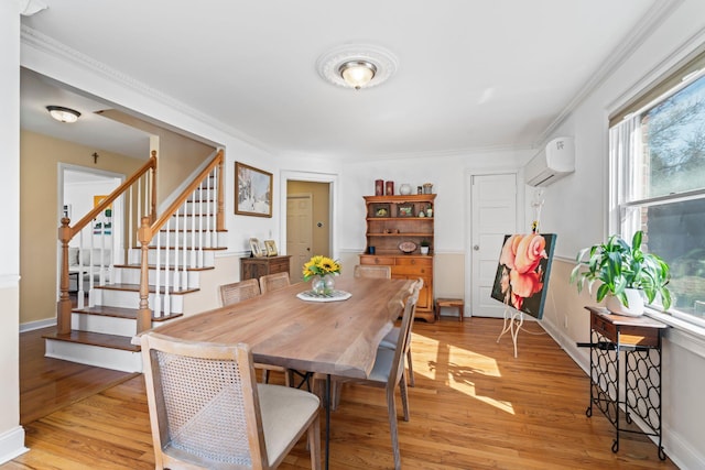 dining area with light wood finished floors, crown molding, stairs, and a wall unit AC