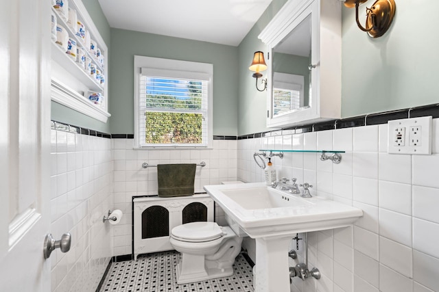 bathroom featuring toilet, tile walls, and wainscoting