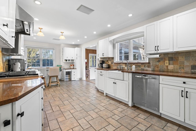 kitchen with dark countertops, decorative backsplash, appliances with stainless steel finishes, white cabinets, and a sink