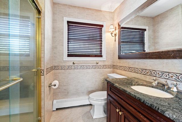 bathroom with vanity, tile walls, a shower stall, and a baseboard radiator