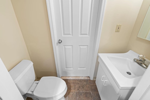 bathroom with vanity, toilet, and stone finish flooring