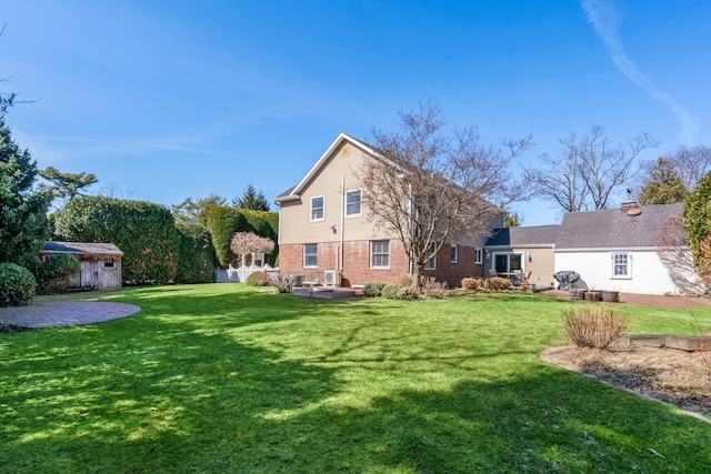 rear view of house featuring an outbuilding, a patio area, a storage unit, and a yard