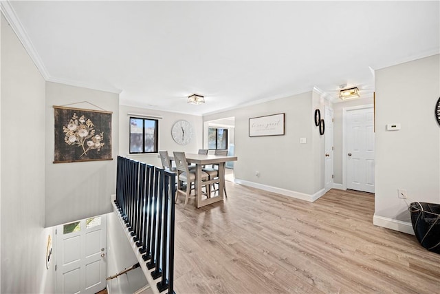 dining space with light wood-style floors, crown molding, and baseboards