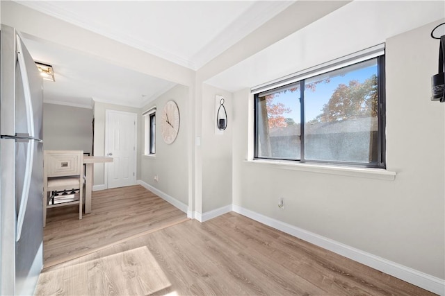 empty room featuring ornamental molding, wood finished floors, and baseboards