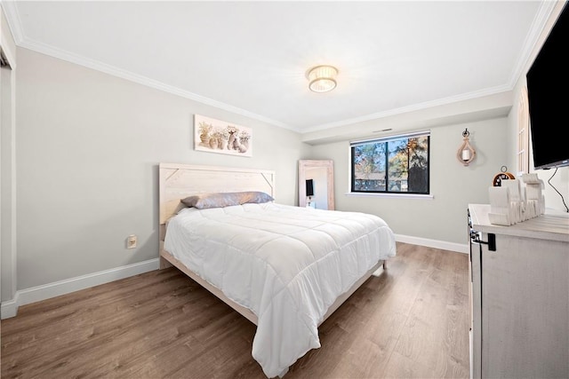 bedroom with ornamental molding, baseboards, and wood finished floors